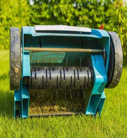 Close up view of electric lawn aerator on green grass isolated. Garden machines concept.