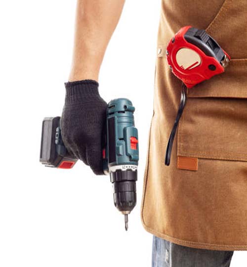 Man in apron and gloves holding cordless screwdriver isolated on white background. Men work, home renovation, construction or carpentry business.