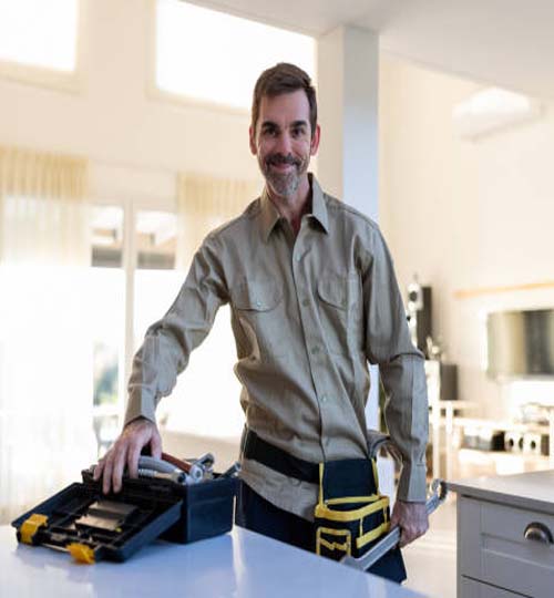 Portrait of a plumber or electrician working at a house with his tools and looking at the camera smiling - home improvement concepts