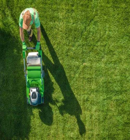 Lawn Moving Aerial Photo. Caucasian Gardener with Gasoline Grass Mower at Work. Landscaping Business. Industrial Theme.