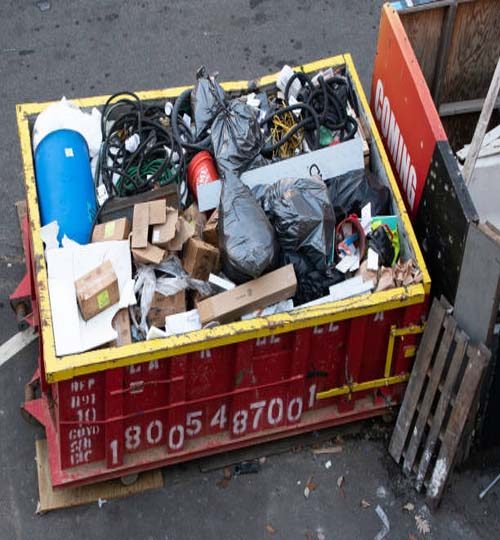 A construction waste container in Manhattan, NYC, filled with a mix of solid household and construction waste, highlighting environmental responsibility and recycling efforts in the city.