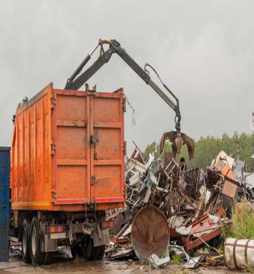 Loading of scrap metal by hydraulic crane, for recycling.